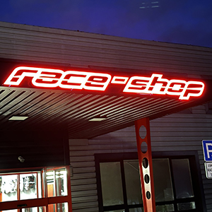 Neon-lit storefront sign above the entrance at dusk, text appears to read 'free shop' in bright red.