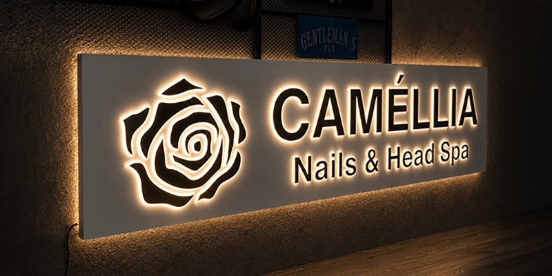 Backlit sign reading 'CAMÉLLIA Nails & Head Spa' with a glowing rose logo on the left side